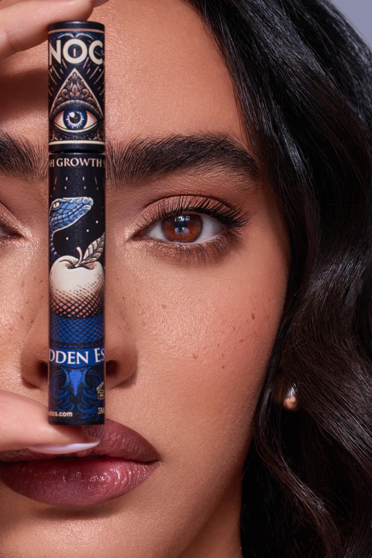 Model hält NOC. Cosmetics Forbidden Essence Lash Growth Wimpernserum vor dem Gesicht – Nahaufnahme mit dichten Wimpern